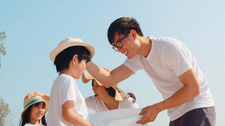 Asian young happy family activists collecting plastic waste on b